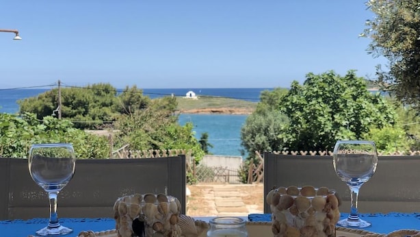 A table with a candle, two decorative shells, and two wine glasses, overlooking a coastal landscape. - Areos Galaxy Apartments With Beach View (Spata-Artemida)