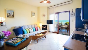 A living room with a sofa, coffee table, and a view of the ocean. - Areos Galaxy Apartments With Beach View (Spata-Artemida)