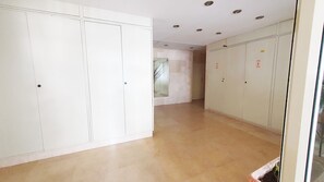 A hallway with white wardrobes, a glass door, and a tiled floor.