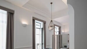 Una habitación de hotel moderna con una cama de madera, un escritorio, una silla, una mesita y una lámpara colgante.
