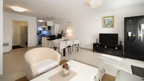 A modern living room with a sofa, a coffee table, a TV, and a dining area with chairs and a table. - House 1581/16219 (Istria - Valbandon), 2250m from the beach (Valbandon)