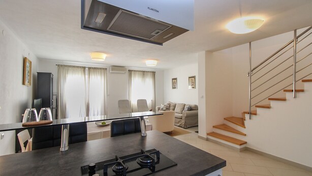 A modern kitchen with a gas stove, a dining area with a table and chairs, a sofa, and a staircase. - House 1581/16219 (Istria - Valbandon), 2250m from the beach (Valbandon)