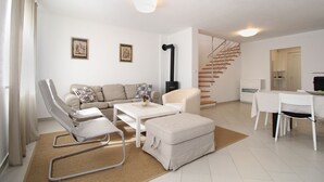 A modern living room with a sofa, armchair, ottoman, and a dining table. A staircase is visible in the background. - House 1581/16219 (Istria - Valbandon), 2250m from the beach (Valbandon)
