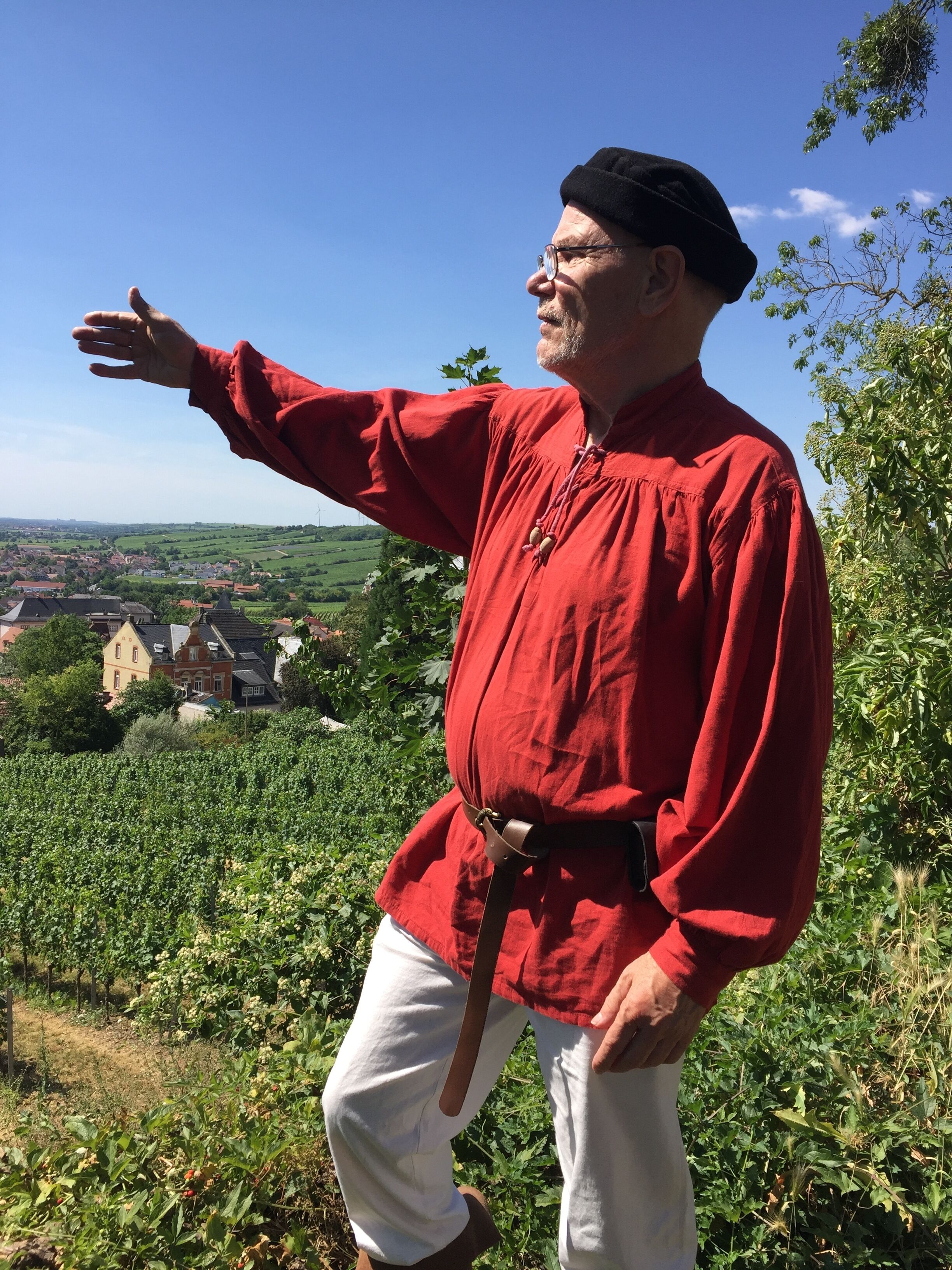 A person standing outdoors with a vineyard in the background.