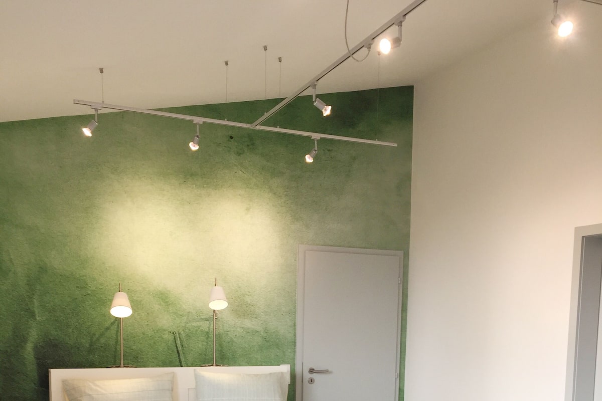 Une chambre à coucher avec un lit, des lampes de chevet, une porte et un mur vert.