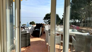 A patio area with wicker furniture, a table with a vase, and a view of the sea.