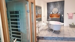 Een moderne badkamer met een vrijstaand bad, een douchecabine met glazen wanden en een wastafelmeubel met spiegel en planken.