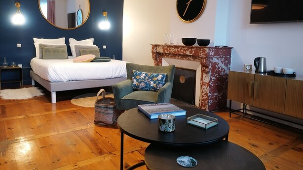 Een moderne slaapkamer met een bed, een ronde spiegel, een klok, een open haard, een televisie en een salontafel.