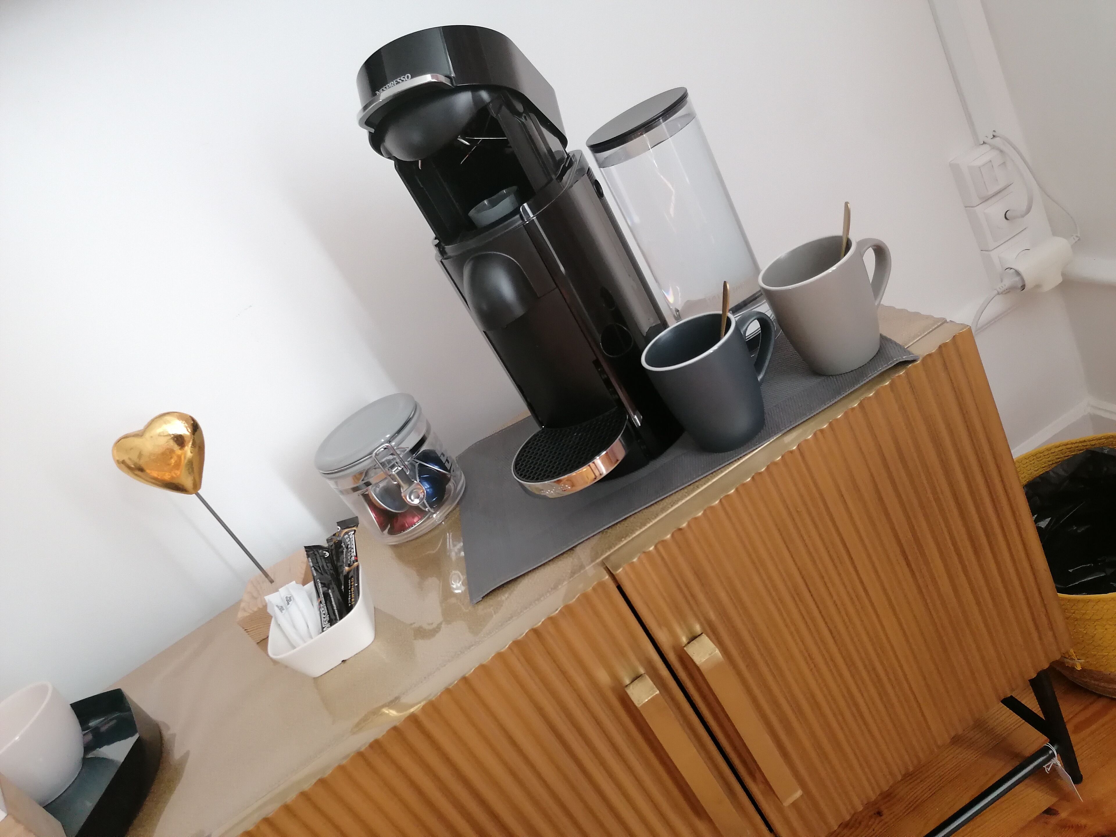 A kitchenette with a coffee maker, a kettle, and a mug on the counter.