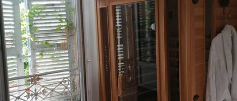 Una sauna de madera con puertas de vidrio, una toalla blanca colgando en la puerta y suelo de madera.