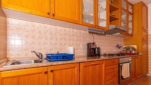 A kitchen with wooden cabinets, a stainless steel sink, a coffee maker, and a toaster. - Apartment Dadi (Crikvenica)