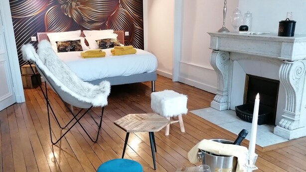 A modern living room with a bed, a fireplace, and a decorative wall. - B&B 43 4 (Le Puy-en-Velay)