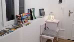 A small, clean room with a white wall, a window, a white chair, and a small table with a lantern. - B&B 43 4 (Le Puy-en-Velay)