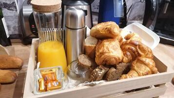 A breakfast tray with croissants, a glass of orange juice, and chocolate bars.