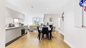 Una cocina moderna con comedor, suelo de madera y una decoración en tonos blancos.