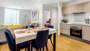 Una cocina moderna con horno integrado y comedor con mesa dispuesta para cuatro.