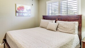 Un dormitorio con una cama grande, una ventana con persianas y un cuadro en la pared.