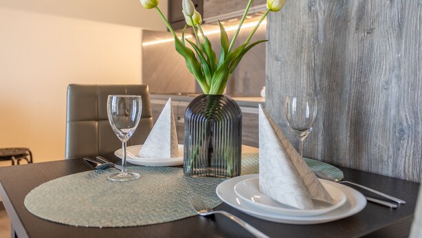 A dining table set with a vase of white tulips, two glasses, and folded napkins. - Vacation apartment by the sea, vacation on the island of Usedom, Apartment AURORA (Świnoujście)