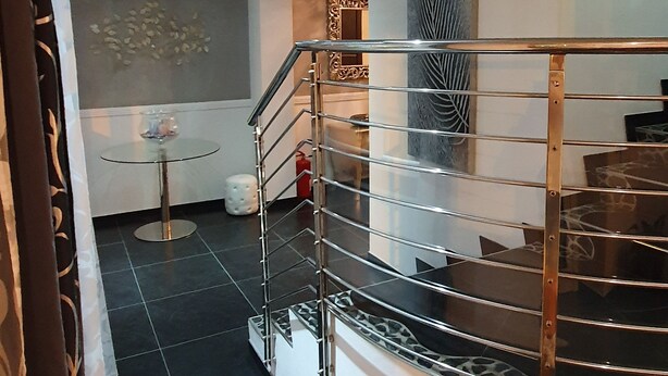 Un interior moderno con una escalera, una mesa de vidrio y una pared decorativa.