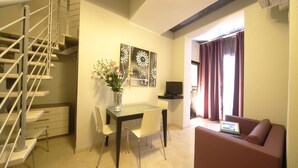 Un espacio habitable compacto con comedor, sofá, televisor y escalera.