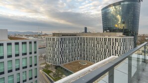 A modern building with a curved glass facade, a courtyard, and a view of the cityscape. - easy-flat Grüner Prater - Balcony Apartments near Metro (Vienna)