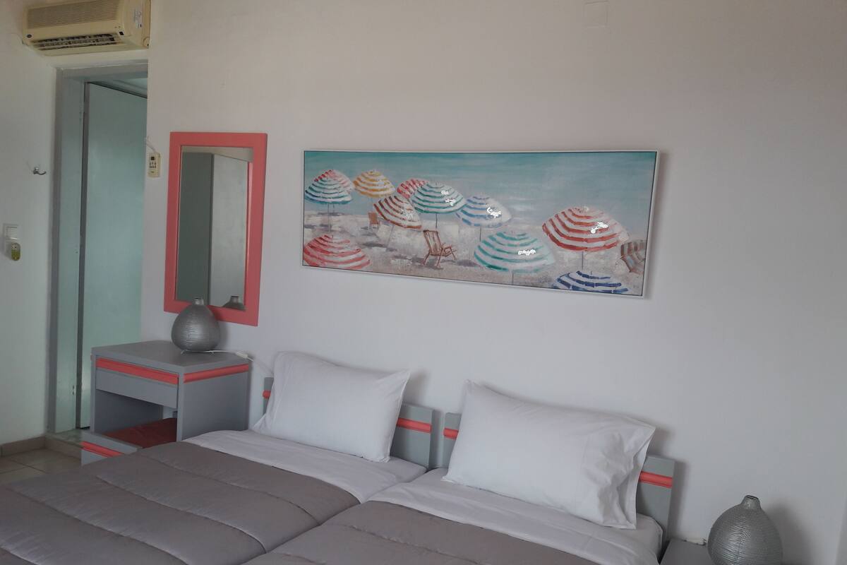 A bedroom with a bed, bedside tables, a mirror, and a painting.