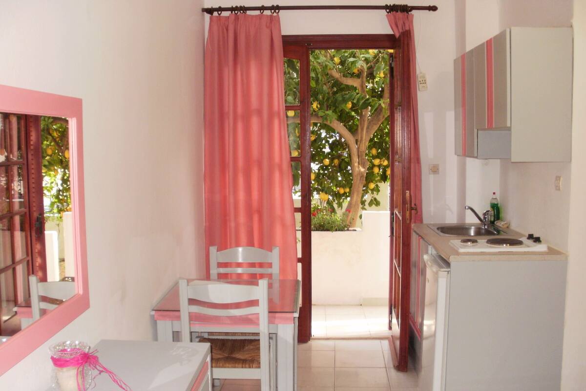 A compact kitchen with a sink, stove, and a dining area with a table and chairs.