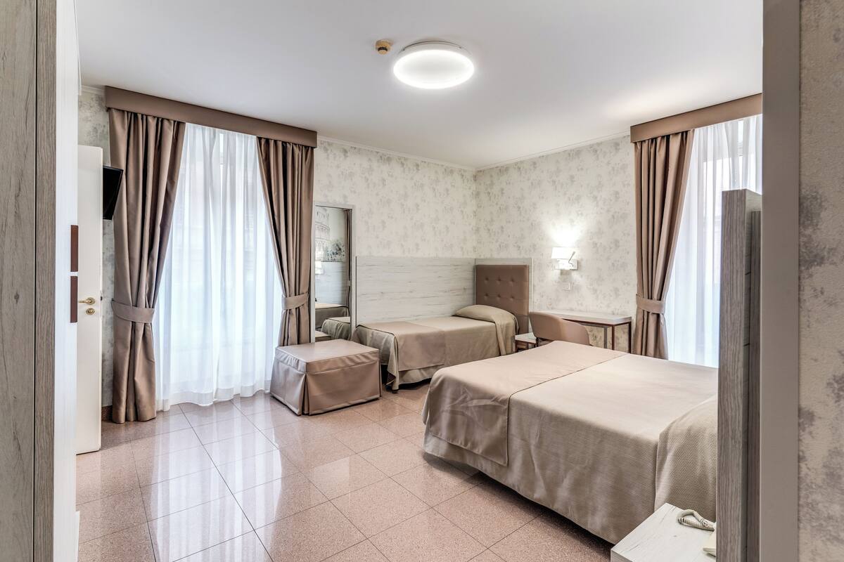 A hotel room with two beds, a sitting area, and a bathroom.