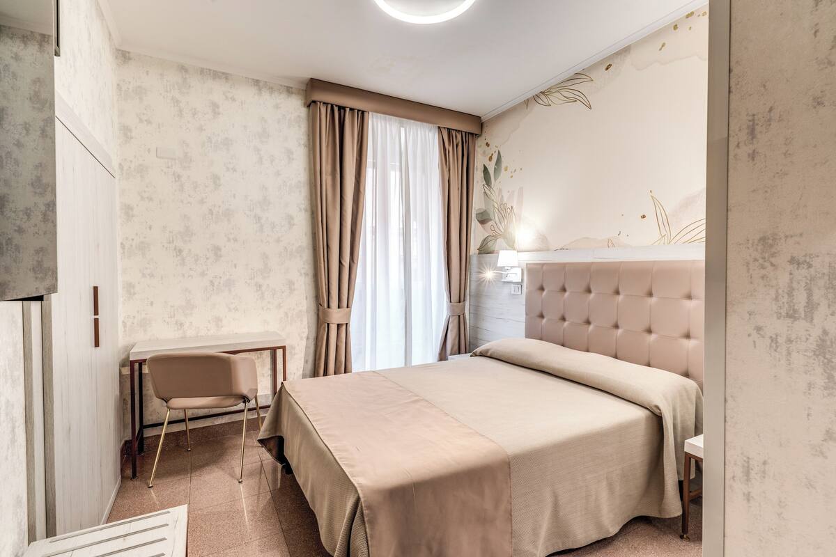 A bedroom with a bed, a desk, and a chair.