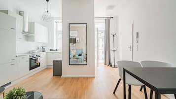 Una cocina moderna con armarios blancos, horno empotrado y comedor con mesa y sillas.
