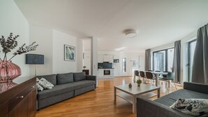 A modern living room with a grey sofa, a wooden coffee table, and a dining area with chairs and a table. - easy-flat Pilgramgasse - Apartments near Metro (Vienna)