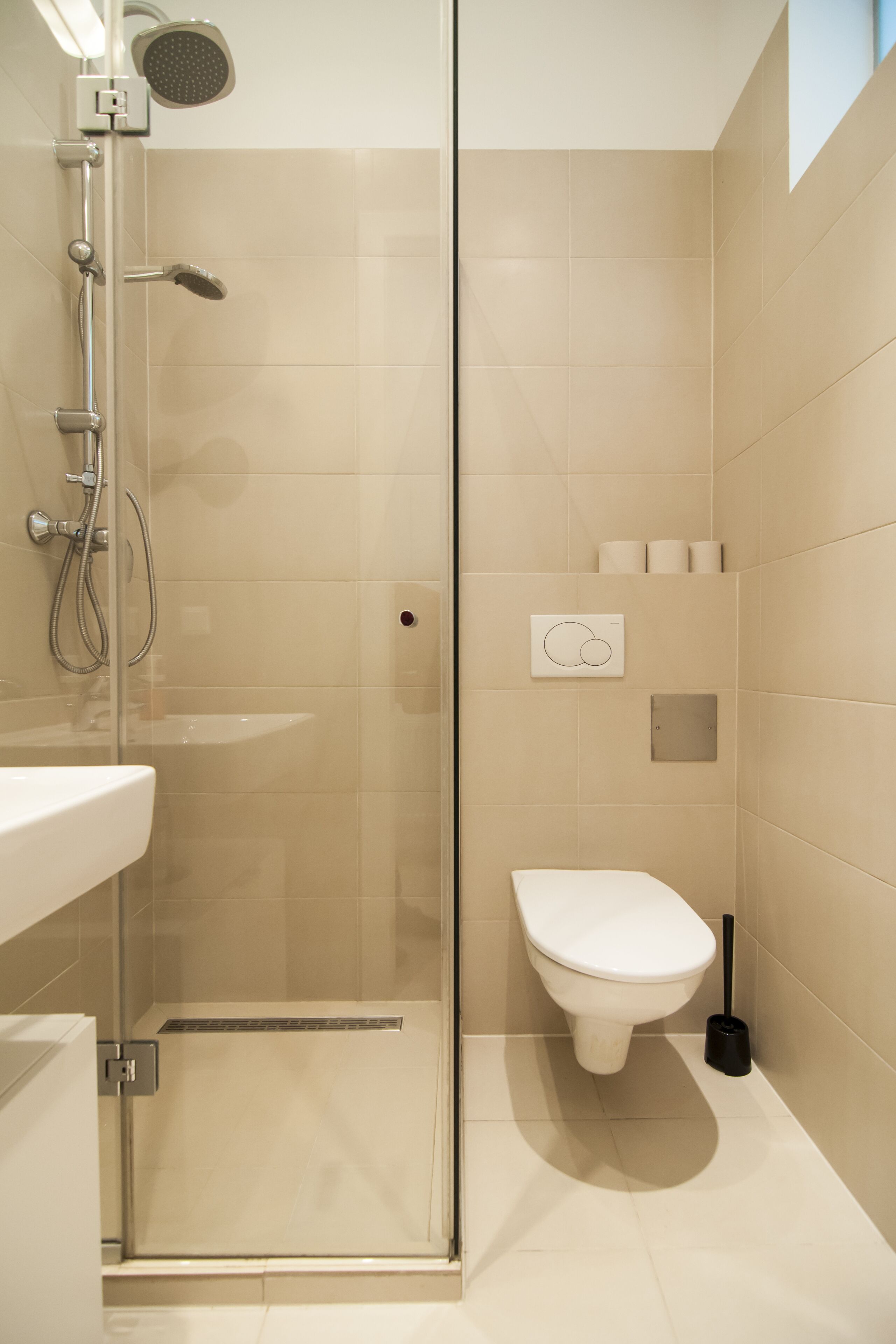 Un baño moderno con ducha de vidrio, lavamanos blanco y retrete.
