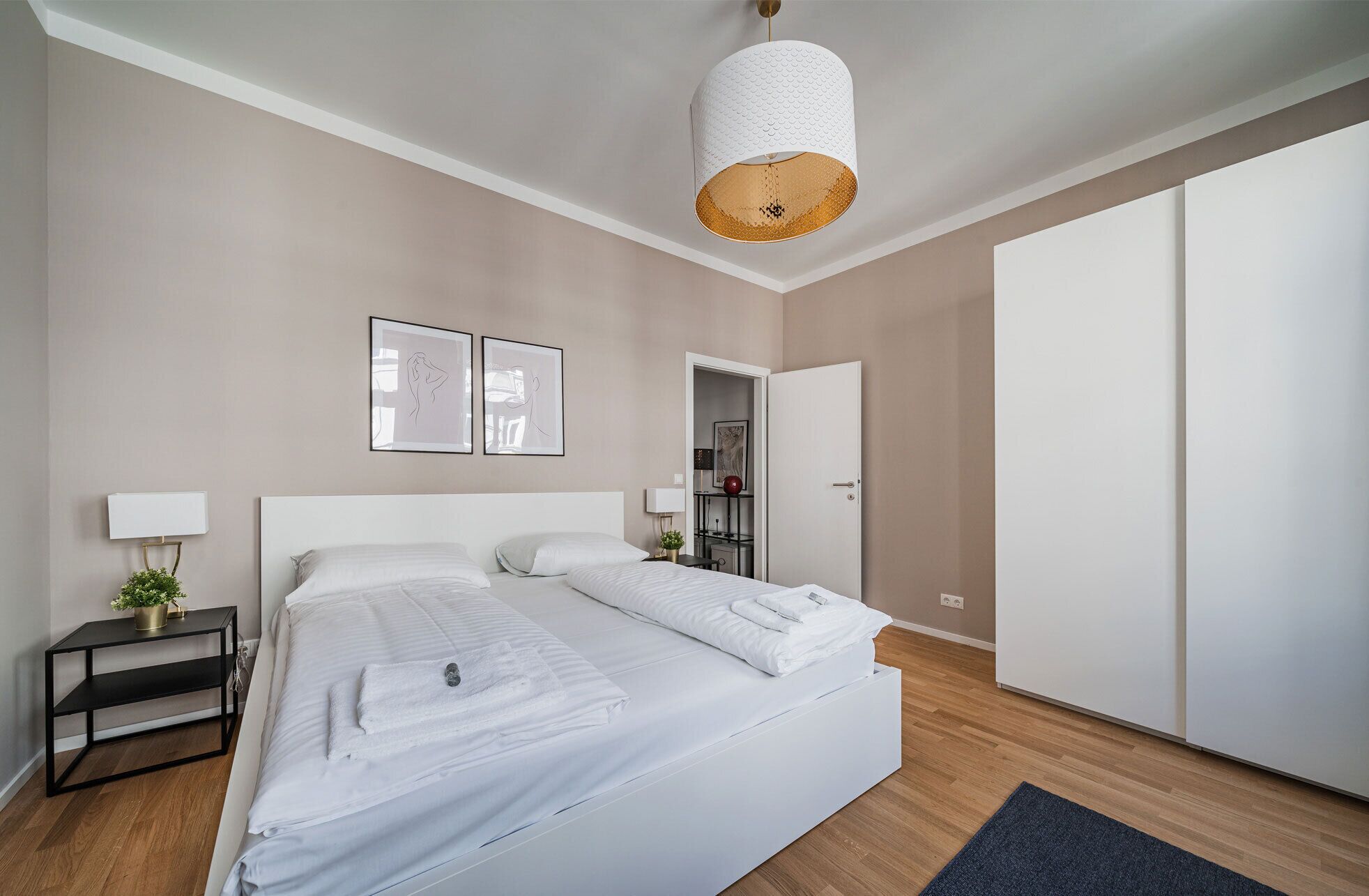 A modern bedroom with a large bed, a bedside table with a lamp, and a wardrobe.