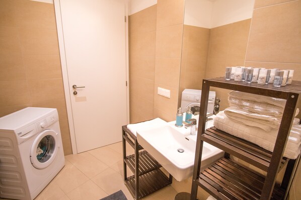 Ein kleines Badezimmer mit Waschmaschine, Waschbecken und Handtuchhalter.