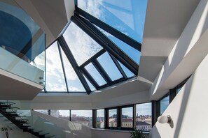 Ein modernes Interieur mit einer Glasstufenkonstruktion, großen Fenstern und Blick auf die Stadtlandschaft.