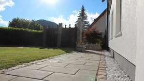 Un patio empedrado con losetas de piedra, un cerco de madera y un muro de piedra.
