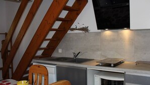 Een kleine keuken met een houten trap, een inbouwmagnetron en een klein spoelbakje.