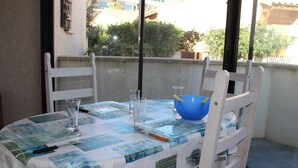 Een tafel gedekt voor twee personen, met een blauwe kom, bestek, een glas en een menu op een tafelkleed met een blauw-wit patroon.
