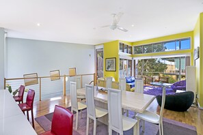 A dining area with a table and chairs, a ceiling fan, and a view of the outdoors.