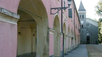 A corridor with pink and yellow walls, arched doorways, and a clock tower in the background.