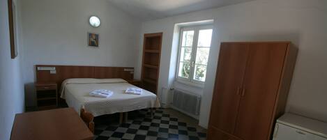 Una habitación con cama, escritorio, armario y ventana.
