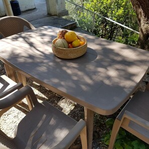 Ett bord med en flätad korg som innehåller frukt, omgivet av plaststolar.