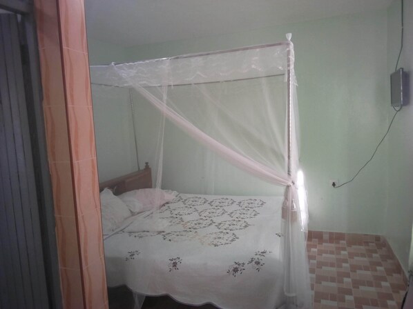 A single bed with a canopy, a wall socket, and a tiled floor. - Choma Zone Hotel (Mwingi)