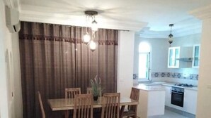 Una sala de estar moderna con comedor, cocina y televisor sobre una mesa de madera.