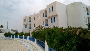 Un edificio blanco con detalles azules y un sendero curvo que lo lleva hacia él.