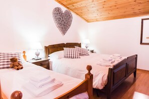 A bedroom with two beds, wooden headboards, and a heart-shaped wall decoration.