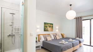 A modern hotel room with a glass shower enclosure, a large bed with two pillows, a bedside table with a lamp, and a view of the outdoors. - Finata  Studios (Corfu)
