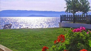 A grassy area with a fence and a bench overlooking a body of water. - Finata  Studios (Corfu)