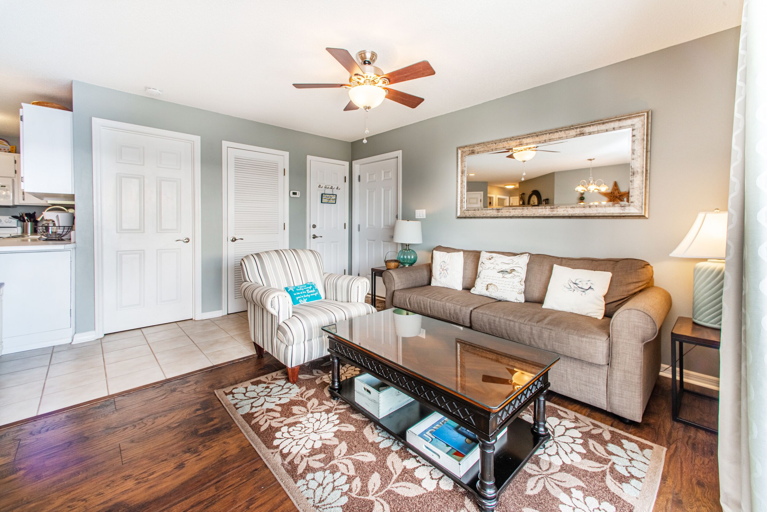A living room with a sofa, armchair, coffee table, and a ceiling fan.