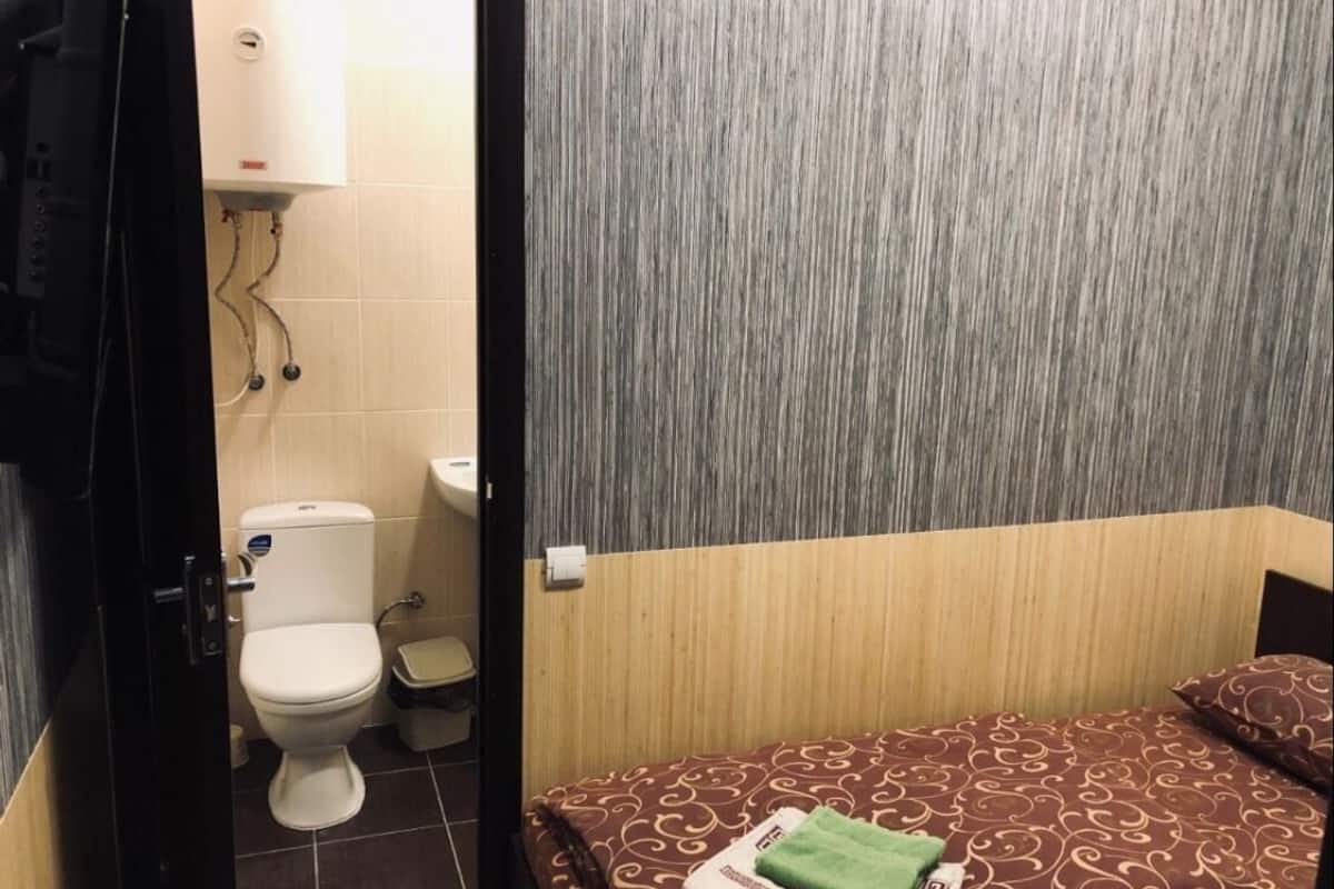 Una habitación pequeña y funcional con cama, inodoro y lavamanos.